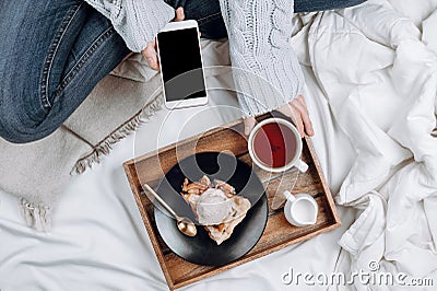 Cozy flatlay of bed with wooden tray with vegan apple pie, ice cream and black tea Stock Photo