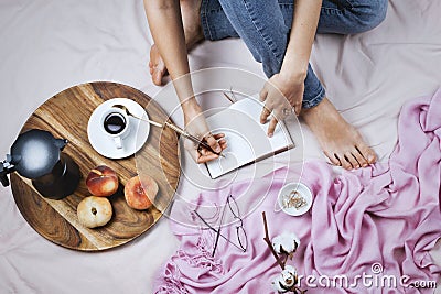 Cozy flatlay with white tanned woman in jeans making notes in her notebook Stock Photo