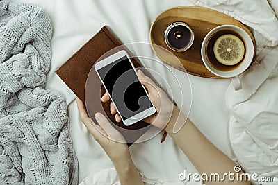 Cozy flatlay of woman`s hands holding smartphone with black scre Stock Photo