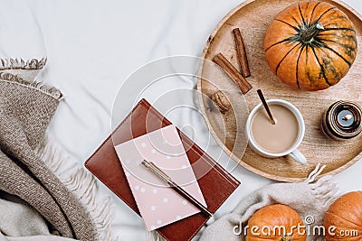 Cozy flatlay with wooden tray, cup of coffee or cocoa, candle, pumpkins, notebooks Stock Photo