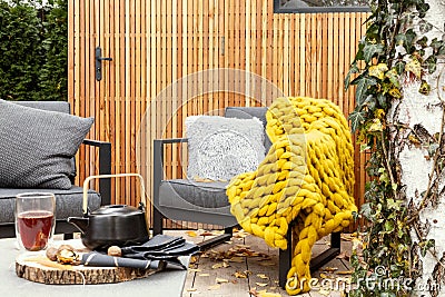 Garden with grey armchairs, yellow blanket and kettle and glass on the table Stock Photo