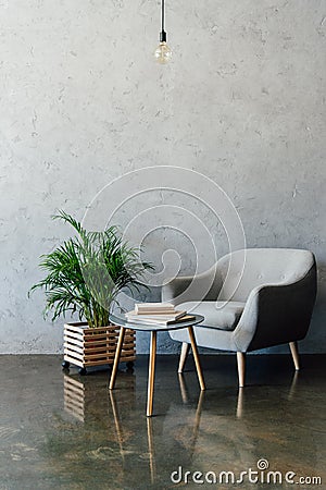 Cozy grey armchair with books on coffee table Stock Photo