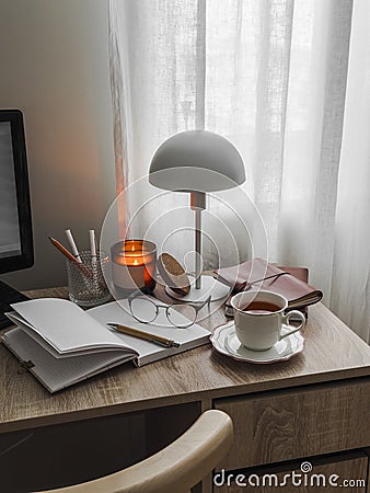 Cozy home desk - Scandinavian style table lamp, candle, work, learning accessories on a wooden table Stock Photo