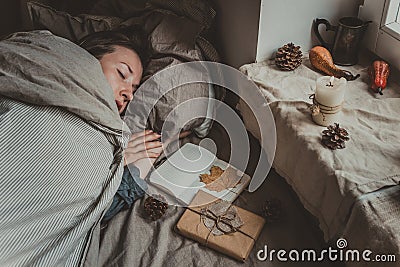 Cozy home. Woman sitting by the window and writing in notepad. Selective focus Stock Photo