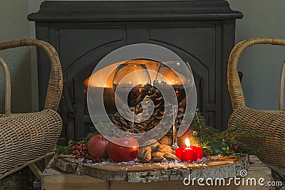 Cozy interior with burning stove, two glass of wine and fruits of tree stump Stock Photo