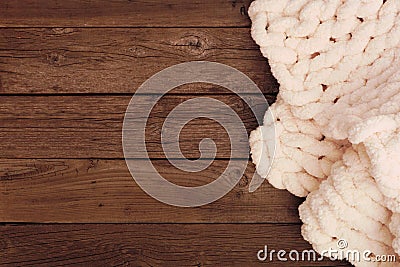 Cozy cream colored knitted thick wool blanket, top view side border on a rustic dark wood background Stock Photo