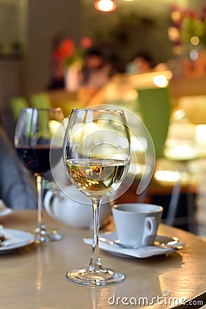 A photo of a cozy modern urban cafe with low warm light, a glass of wine on the table and noone inside Stock Photo