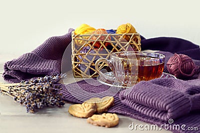 Cozy needlework time: a cup of tea on purple knitwear, skeins of multi-colored threads, a bouquet of lavender, heart-shaped Stock Photo