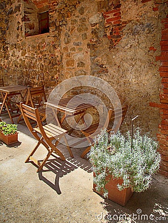 Cozy outdoor cafe with wooden table and chairs in small village, Tuscany, Italy Stock Photo