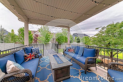 Cozy outdoor deck with fire pit table and woven sofas with blue cushions Stock Photo