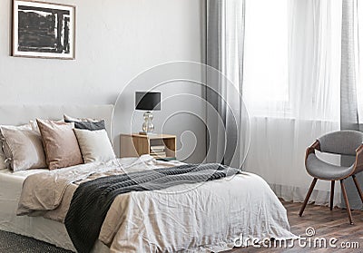 Cozy pillows on comfortable big king size bed in bright bedroom interior in elegant apartment Stock Photo