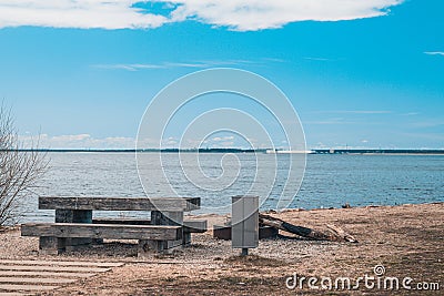 A cozy place for a picnic in the summer near a pond - a wooden table, benches and a trash can, near a fire pit, Latvia Stock Photo