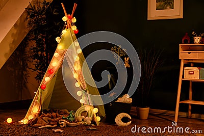 Cozy play tent for kids with glowing garland in room interior Stock Photo