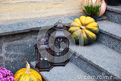 Cozy porch of the house with vintage lanterns in fall time. House entrance staircase decorated for autumn holidays, fall flowers a Stock Photo