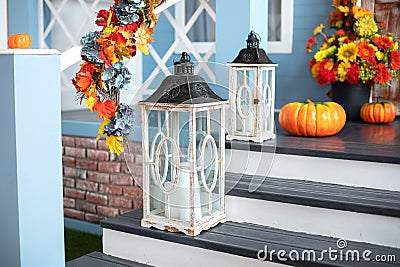 Cozy porch of the house with wooden lanterns in fall time. Halloween design home with yellow fall leaves and lamps. Stock Photo