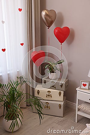 Cozy room interior with heart shaped balloons and storage trunks near window. Valentine Day celebration Stock Photo