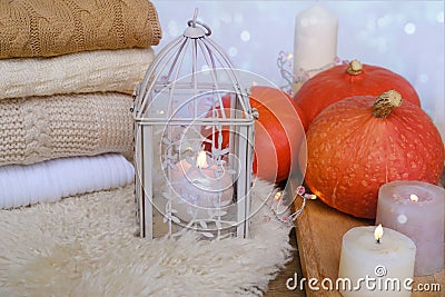 Cozy Scandinavian hyugge, three orange pumpkins, white candles, woolen clothes, sheepskin, halloween concept, cozy home, Stock Photo