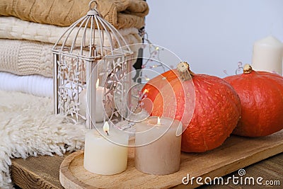 Cozy Scandinavian hyugge, three orange pumpkins, white candles, woolen clothes, sheepskin, halloween concept, cozy home, Stock Photo