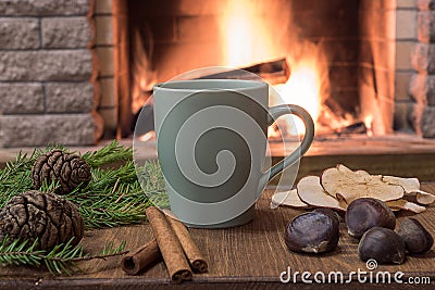 Cozy scene near fireplace with mug of hot tea, warm scarf and candles Stock Photo