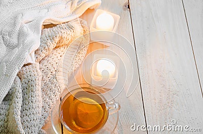 Cozy and soft winter background. Warm sweaters or blankets, candles, cup of tea. Stock Photo