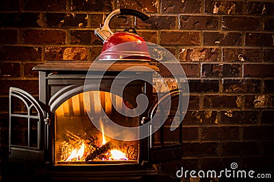 Cozy, warm fire heating a kettle against a brick hearth Stock Photo