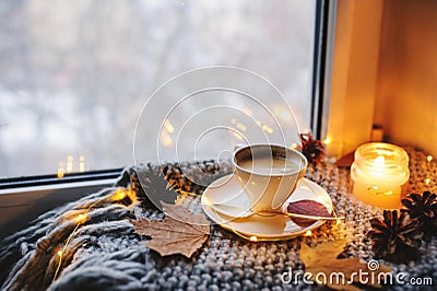 Cozy winter or autumn morning at home. Hot coffee with gold metallic spoon, warm blanket, garland and candle lights Stock Photo