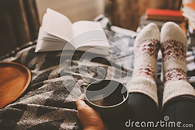 cozy winter day at home with cup of hot tea, book and warm socks Stock Photo