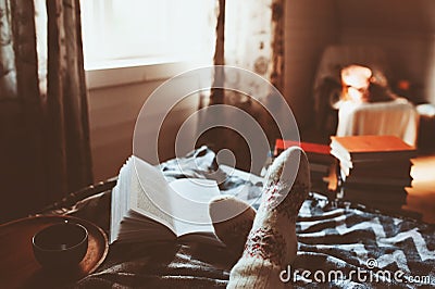 Cozy winter day at home with cup of hot tea, book and warm socks Stock Photo