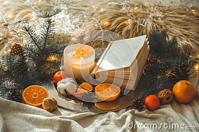 Book and Tangerines in a winter composition, Christmas trees, candles, cones, cotton, cinnamon. Symbol of New Year and Christmas Stock Photo