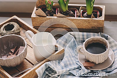 Cozy winter morning at home. Coffee, milk and chocolate on wooden tray. Huacinth flowers on background. Warm mood Stock Photo