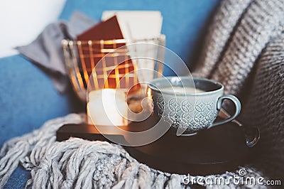 Cozy winter weekend at home. Morning with coffee or cocoa, books, warm knitted blanket and nordic style chair. Hygge concept. Stock Photo