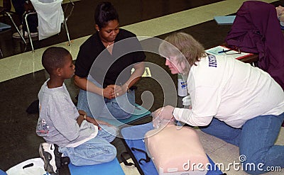 A CPR instructor teaches a boy and his mother at a communityeventr Editorial Stock Photo