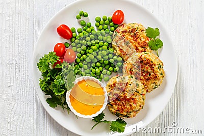 crab cakes with sauce, green peas, tomatoes Stock Photo
