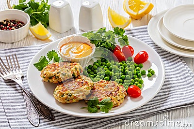 crab cakes with sauce, green peas, tomatoes Stock Photo