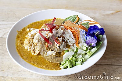 Crabmeat curry sauce with fermented rice noodle and side dishes in white plate on the wooden table. Stock Photo