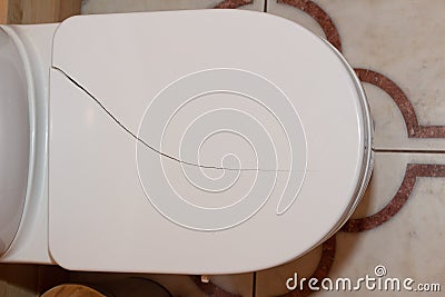 Crack on the toilet lid. Broken toilet lid. Close-up. View from above Stock Photo