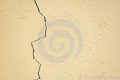 Crack in the yellow plastered wall Stock Photo