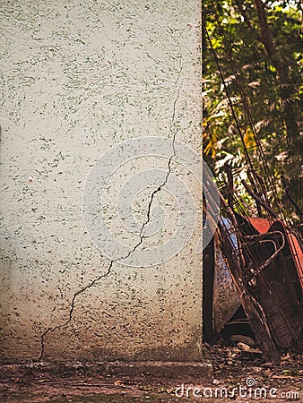 A cracked wall with wheelbarrows and tools leaning against it in Stock Photo