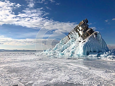 Cracks on the surface of the blue ice. Frozen lake Baikal in winter mountains. It is snowing. The hills of pines. Carpathian Russi Stock Photo