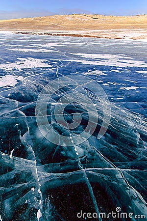 Cracks on the surface of the blue ice. Frozen lake in winter mountains on Lake Baikal Stock Photo