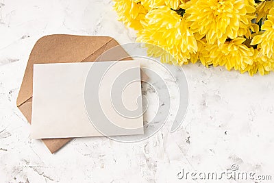 Craft kraft paper envelope and yellow chrysanthemum flowers on a light background. Flat workspace. Flat lay, top view Stock Photo