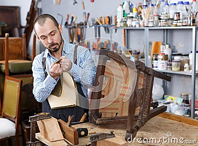 Craftsman reupholstering chair in workshop Stock Photo