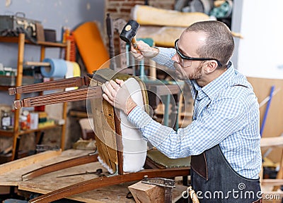 Craftsman reupholstering chair in workshop Stock Photo