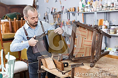 Craftsman reupholstering chair in workshop Stock Photo