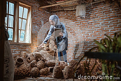 craftswoman in veil holding tablet checking water hyacinth woven crafts Stock Photo