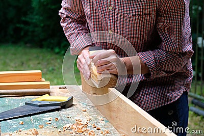 Craftswoman working with carpentry plane outdoors. Close-up view. Woodworking concept Stock Photo