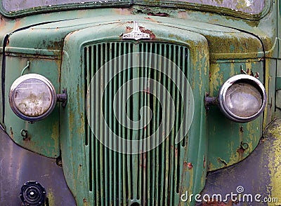 Close up of the front of an old abandoned rusting green truck covered in moss Editorial Stock Photo