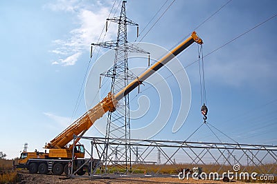 A crane installs a high voltage power line in an industrial suburb Stock Photo