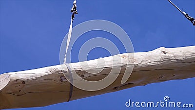 Crane with log on background of sky. Clip. Log is moved with crane on construction site for wooden house. On background Stock Photo