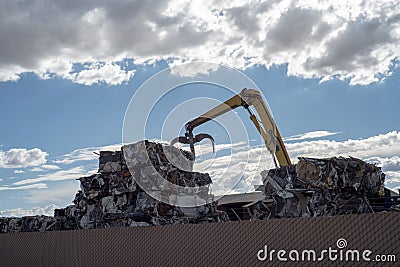 Crane stacking cubes of compressed metal at recycling center Editorial Stock Photo